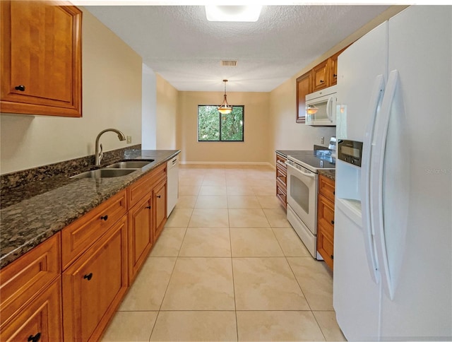 kitchen with pendant lighting, dark stone counters, a textured ceiling, sink, and white appliances