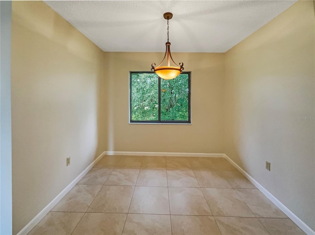 tiled empty room featuring a textured ceiling