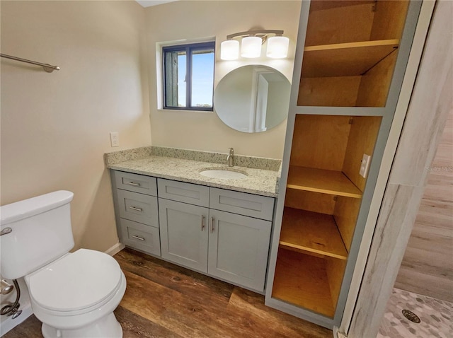 bathroom with a shower, hardwood / wood-style flooring, vanity, and toilet