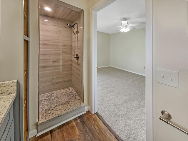 bathroom featuring ceiling fan, vanity, hardwood / wood-style floors, and a tile shower