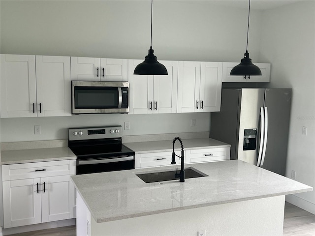 2572 SW 159th Ln, Ocala, FL 34473 - kitchen featuring appliances with stainless steel finishes, a sink, white cabinetry, hanging light fixtures, and light wood finished floors