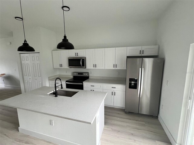 2572 SW 159th Ln, Ocala, FL 34473 - kitchen with appliances with stainless steel finishes, a sink, light wood finished floors, white cabinets, and vaulted ceiling