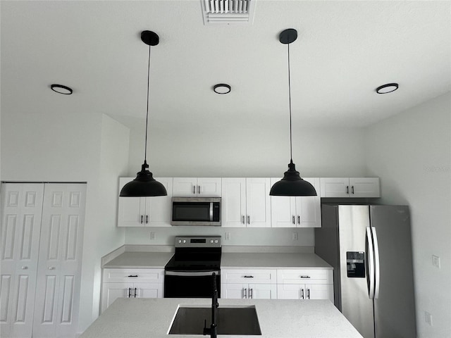 kitchen featuring hanging light fixtures, stainless steel appliances, and white cabinets