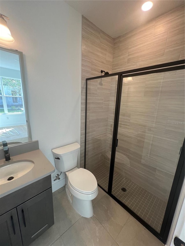 bathroom with tile patterned flooring, vanity, toilet, and a shower with shower door