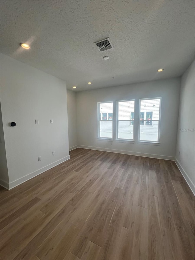 unfurnished room featuring a textured ceiling and hardwood / wood-style flooring