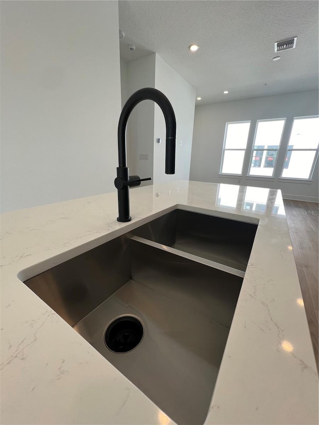 details with light stone counters, a textured ceiling, and sink