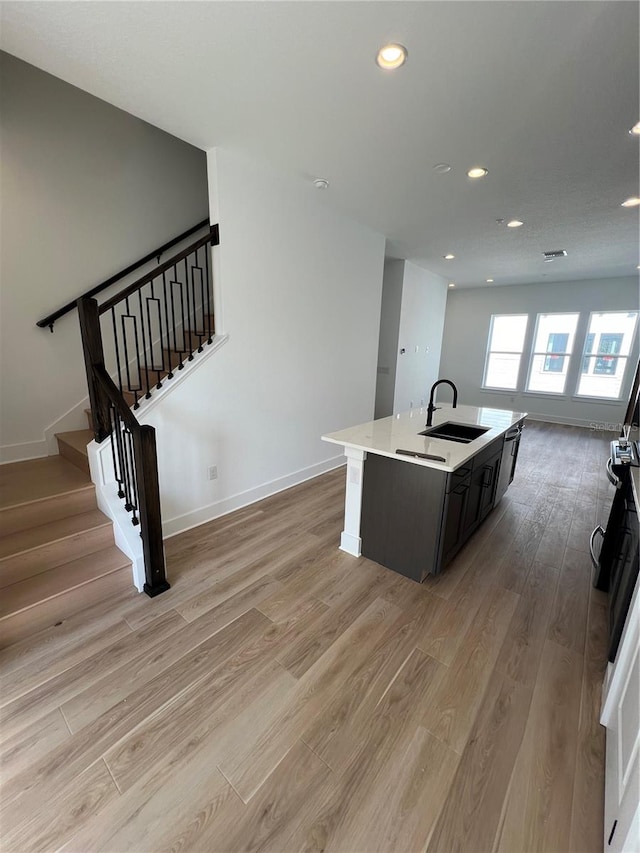 kitchen featuring sink, a kitchen island with sink, light hardwood / wood-style floors, and stainless steel dishwasher