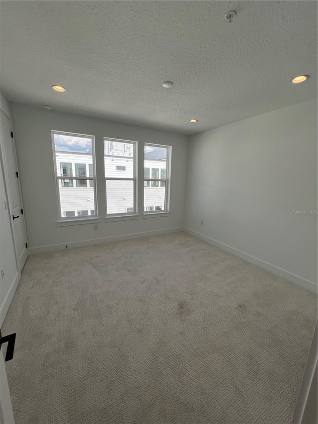 unfurnished room featuring light colored carpet and a textured ceiling