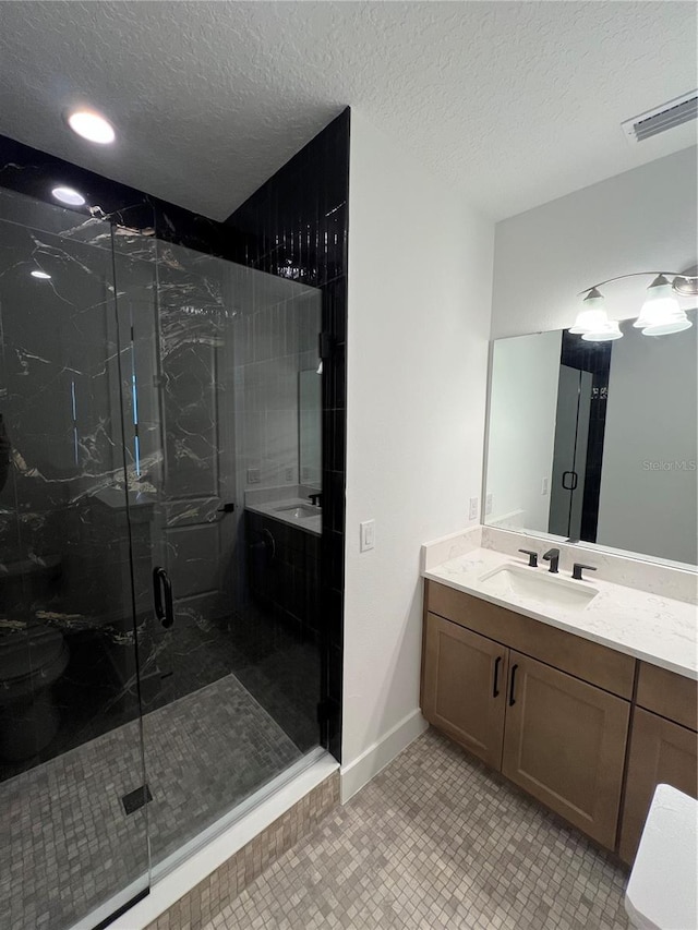 bathroom with a textured ceiling, tile patterned flooring, vanity, and a shower with door