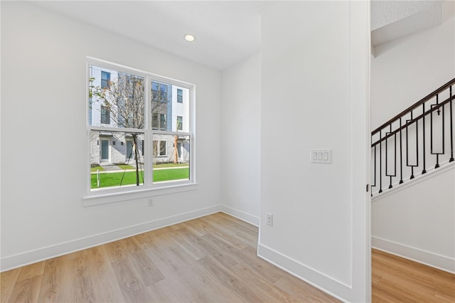 unfurnished room featuring stairs, recessed lighting, light wood-type flooring, and baseboards