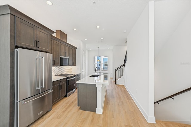 2110 Whitney Marsh Aly, Orlando, FL 32804 - kitchen with appliances with stainless steel finishes, dark brown cabinetry, an island with sink, light wood-style flooring, and recessed lighting