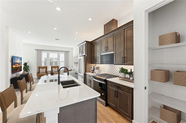2110 Whitney Marsh Aly, Orlando, FL 32804 - kitchen featuring stainless steel appliances, a sink, dark brown cabinets, a center island with sink, and open floor plan