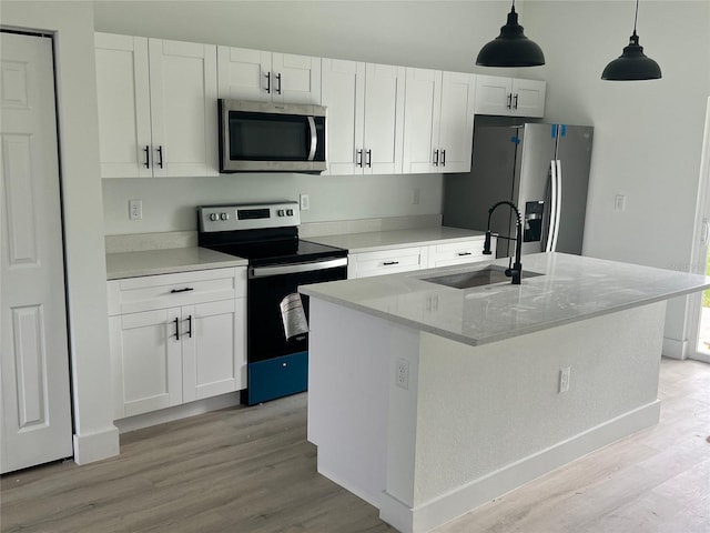 kitchen featuring a kitchen island with sink, stainless steel appliances, sink, and white cabinetry