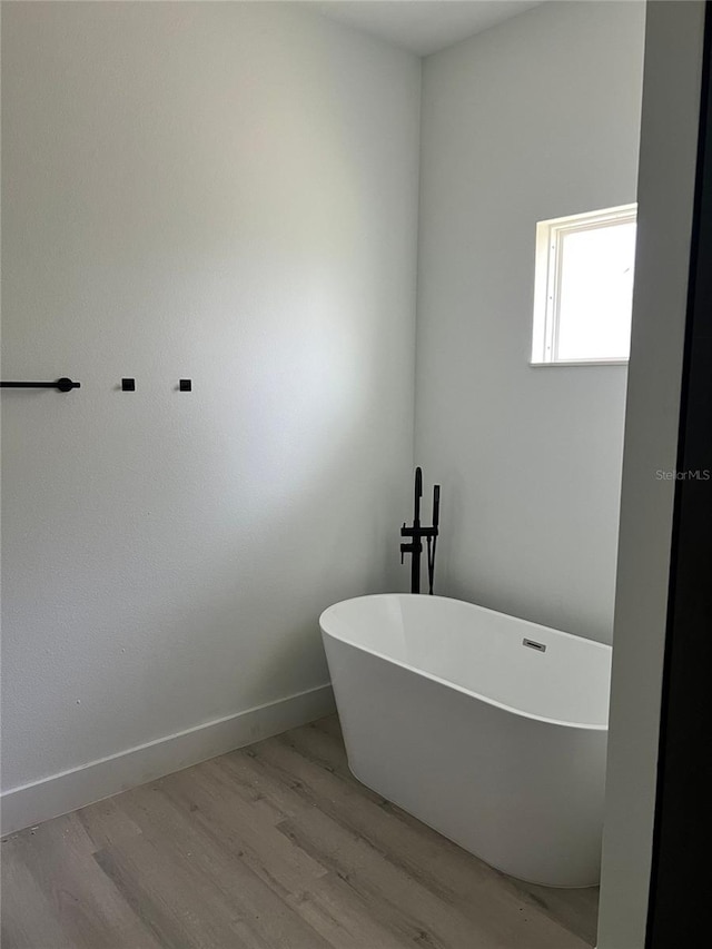 bathroom with wood-type flooring and a washtub