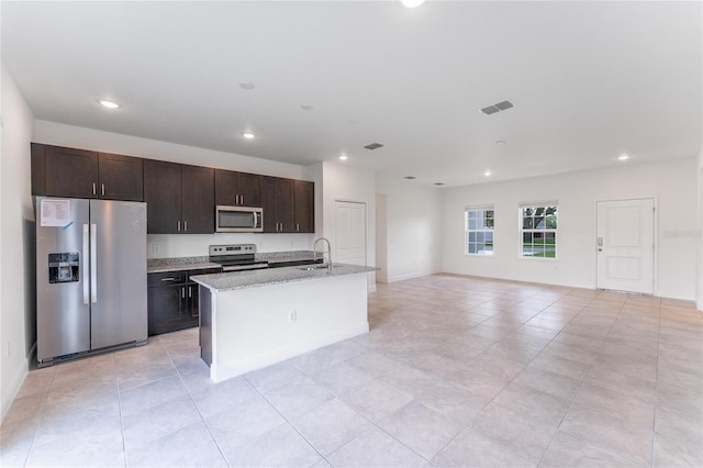 kitchen with appliances with stainless steel finishes, a center island with sink, dark brown cabinetry, and sink