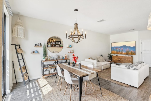 dining area featuring wood-type flooring and a notable chandelier