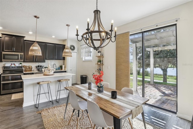 dining space featuring sink, dark wood-type flooring, and a chandelier