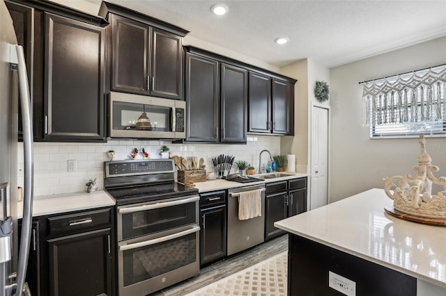 kitchen featuring appliances with stainless steel finishes, light hardwood / wood-style floors, sink, and tasteful backsplash