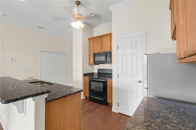 kitchen featuring sink, black appliances, dark stone countertops, crown molding, and hardwood / wood-style floors