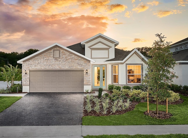 view of front facade featuring a yard, a garage, and french doors