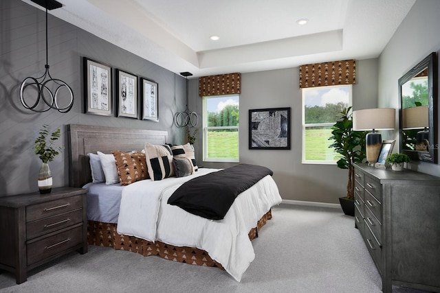 bedroom featuring light colored carpet and a tray ceiling