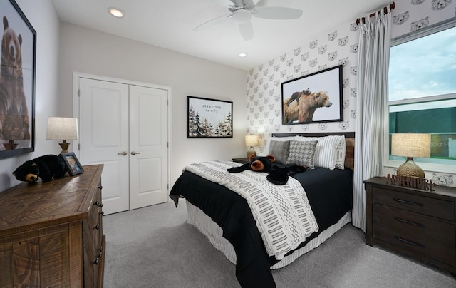 bedroom with ceiling fan, light colored carpet, and a closet