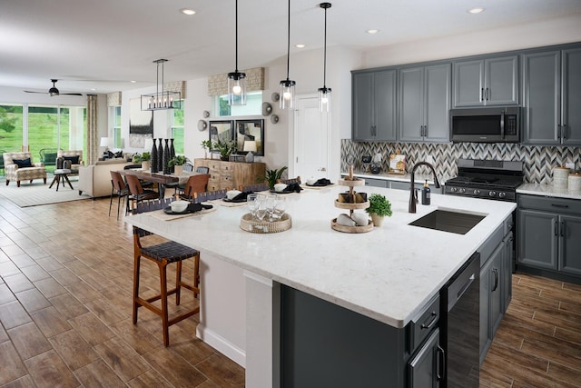 kitchen featuring dark hardwood / wood-style flooring, stainless steel appliances, a kitchen island with sink, and sink