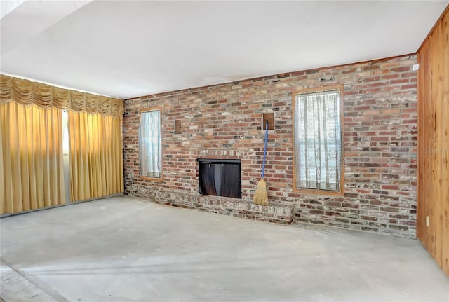 unfurnished living room featuring brick wall, a brick fireplace, and concrete floors