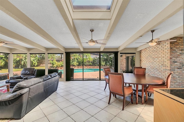 sunroom / solarium with beam ceiling, a skylight, and ceiling fan