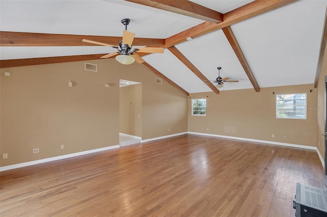 unfurnished living room with light wood-type flooring, plenty of natural light, vaulted ceiling with beams, and ceiling fan