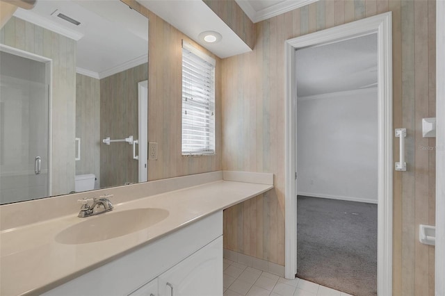 bathroom featuring a shower with shower door, toilet, vanity, ornamental molding, and tile patterned flooring