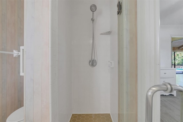 bathroom with toilet, wood walls, tile patterned floors, and tiled shower