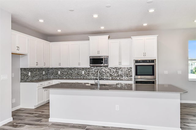 kitchen with an island with sink, white cabinets, appliances with stainless steel finishes, and sink