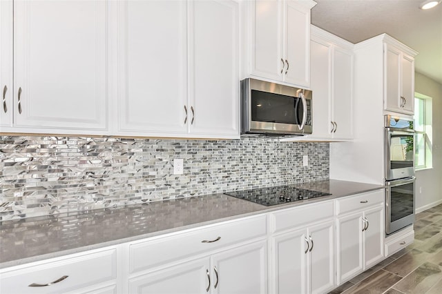 kitchen featuring wood-type flooring, white cabinets, appliances with stainless steel finishes, and backsplash