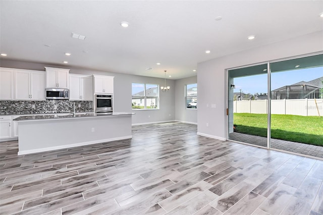 kitchen with light wood-type flooring, decorative backsplash, white cabinetry, and stainless steel appliances