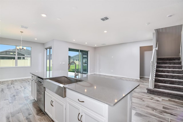 kitchen with an island with sink, a wealth of natural light, white cabinetry, and sink