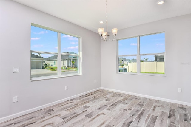 unfurnished room with light wood-type flooring, a chandelier, and a wealth of natural light