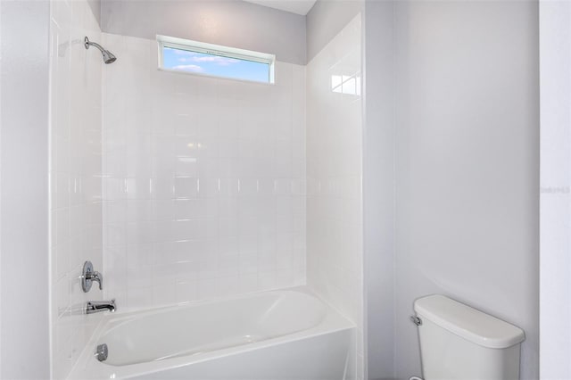 bathroom with tiled shower / bath combo and toilet