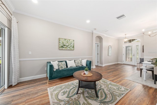 living room featuring ornamental molding, an inviting chandelier, and hardwood / wood-style floors