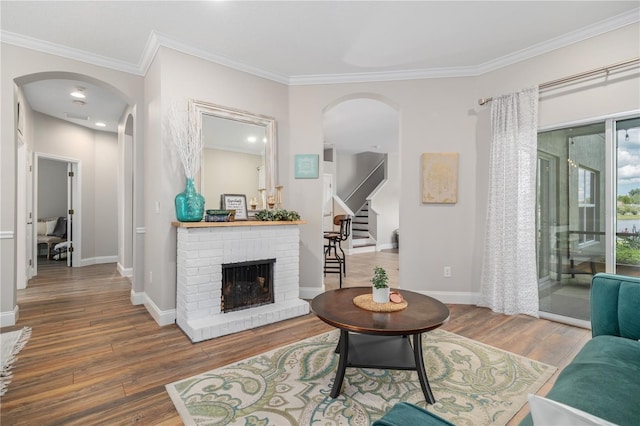 living room with a brick fireplace, hardwood / wood-style flooring, and crown molding