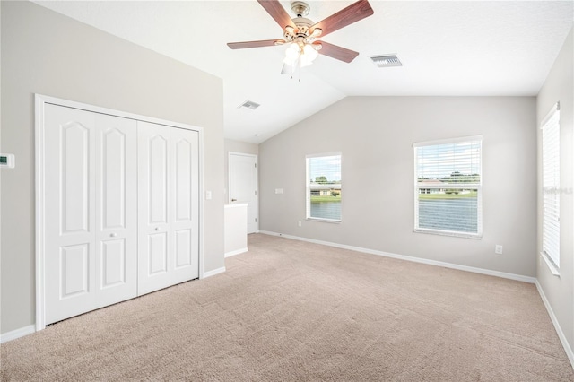 unfurnished bedroom featuring vaulted ceiling, light carpet, ceiling fan, and a closet