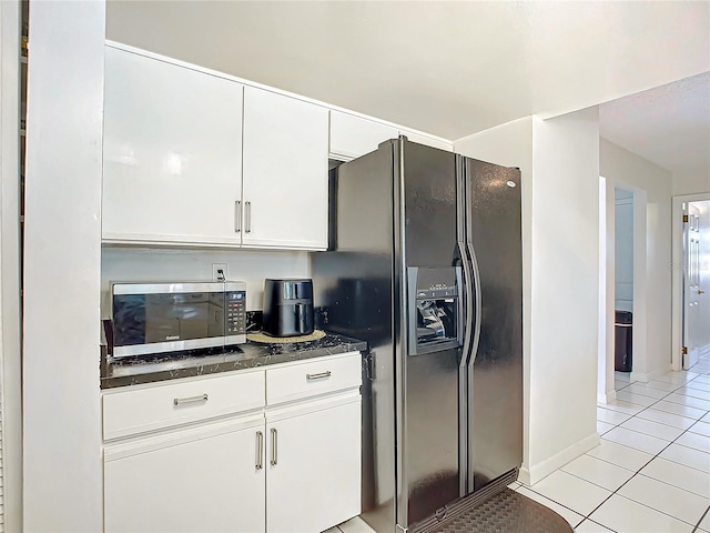 2281 E Union Cir, Deltona, FL 32725 - kitchen with dark stone countertops, stainless steel microwave, black refrigerator with ice dispenser, white cabinetry, and light tile patterned flooring