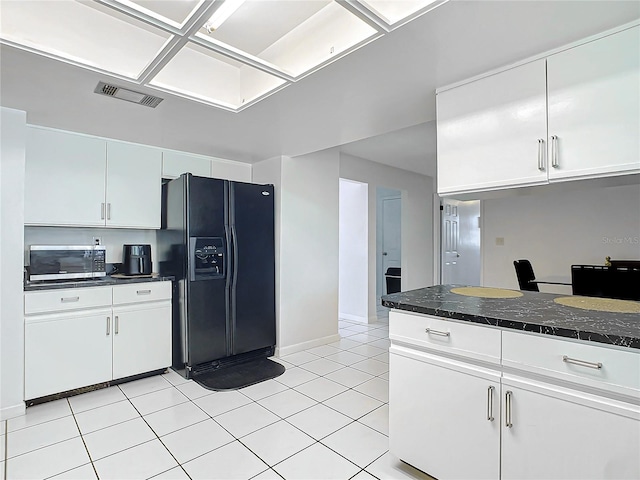 kitchen featuring white cabinets, light tile patterned floors, and black fridge