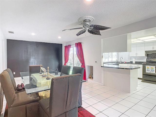 dining space with sink, a textured ceiling, light tile patterned floors, and ceiling fan