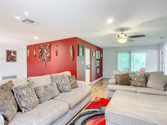 living room featuring light hardwood / wood-style floors, a textured ceiling, and ceiling fan