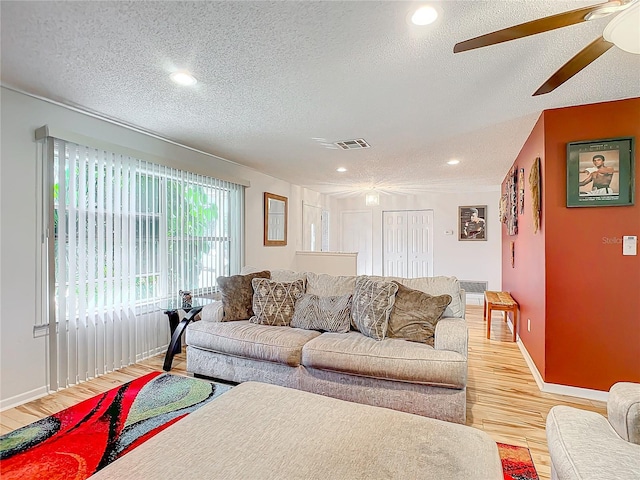 living room featuring ceiling fan, a textured ceiling, and light hardwood / wood-style flooring