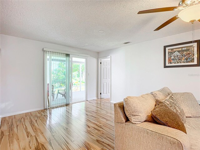 2281 E Union Cir, Deltona, FL 32725 - living room featuring baseboards, light wood-type flooring, a ceiling fan, and a textured ceiling