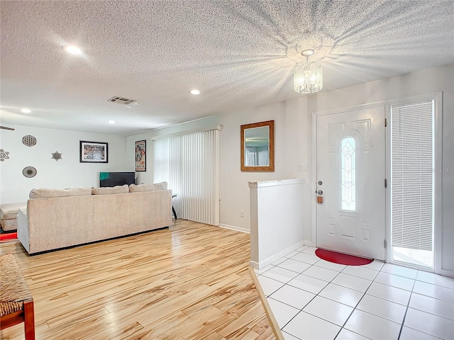 entrance foyer featuring light hardwood / wood-style floors, an inviting chandelier, and a textured ceiling