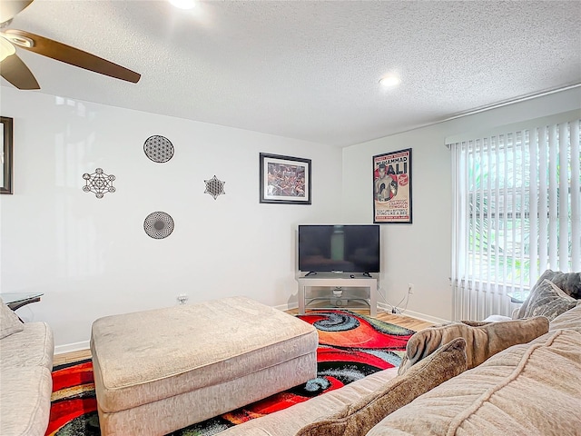 living room with a textured ceiling, wood-type flooring, and ceiling fan