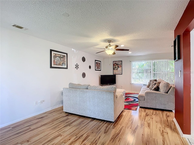 living room featuring ceiling fan, a textured ceiling, and light hardwood / wood-style flooring